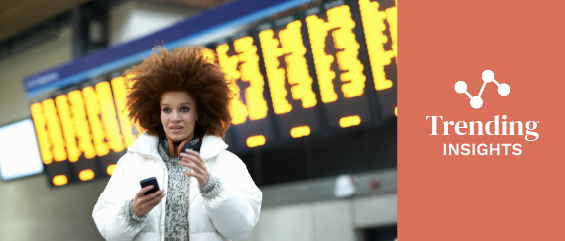 Young woman at train station, holding smartphone