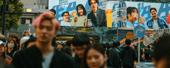 a crowd of people walking down a street next to tall buildings at Shibuya Station